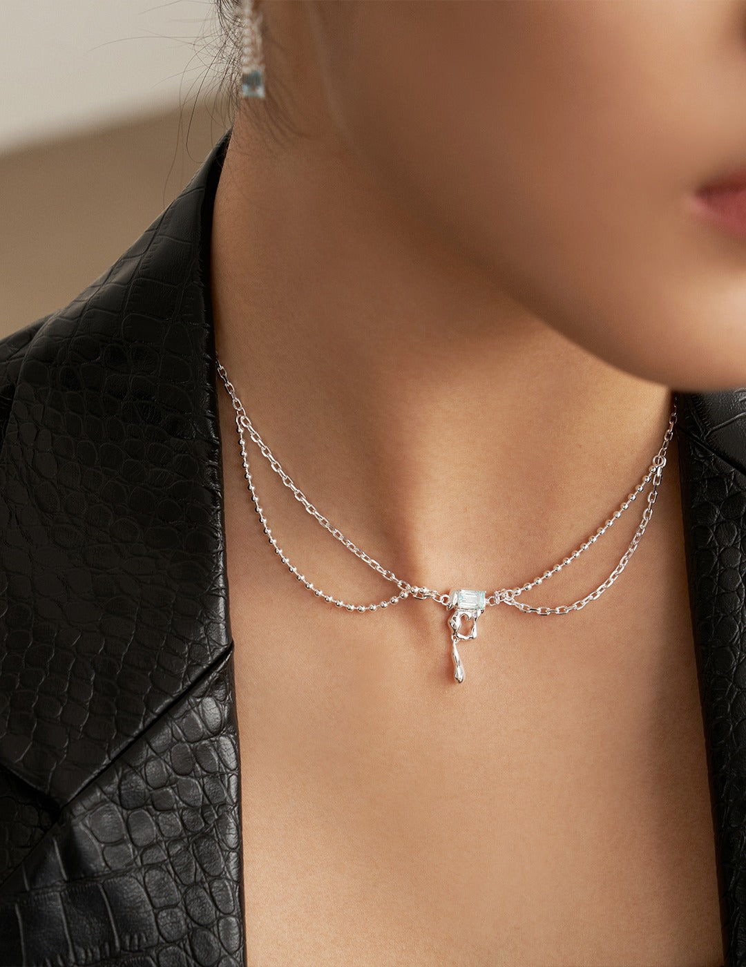 Silver necklace with light blue square pendant and hook drop charm on collarbone