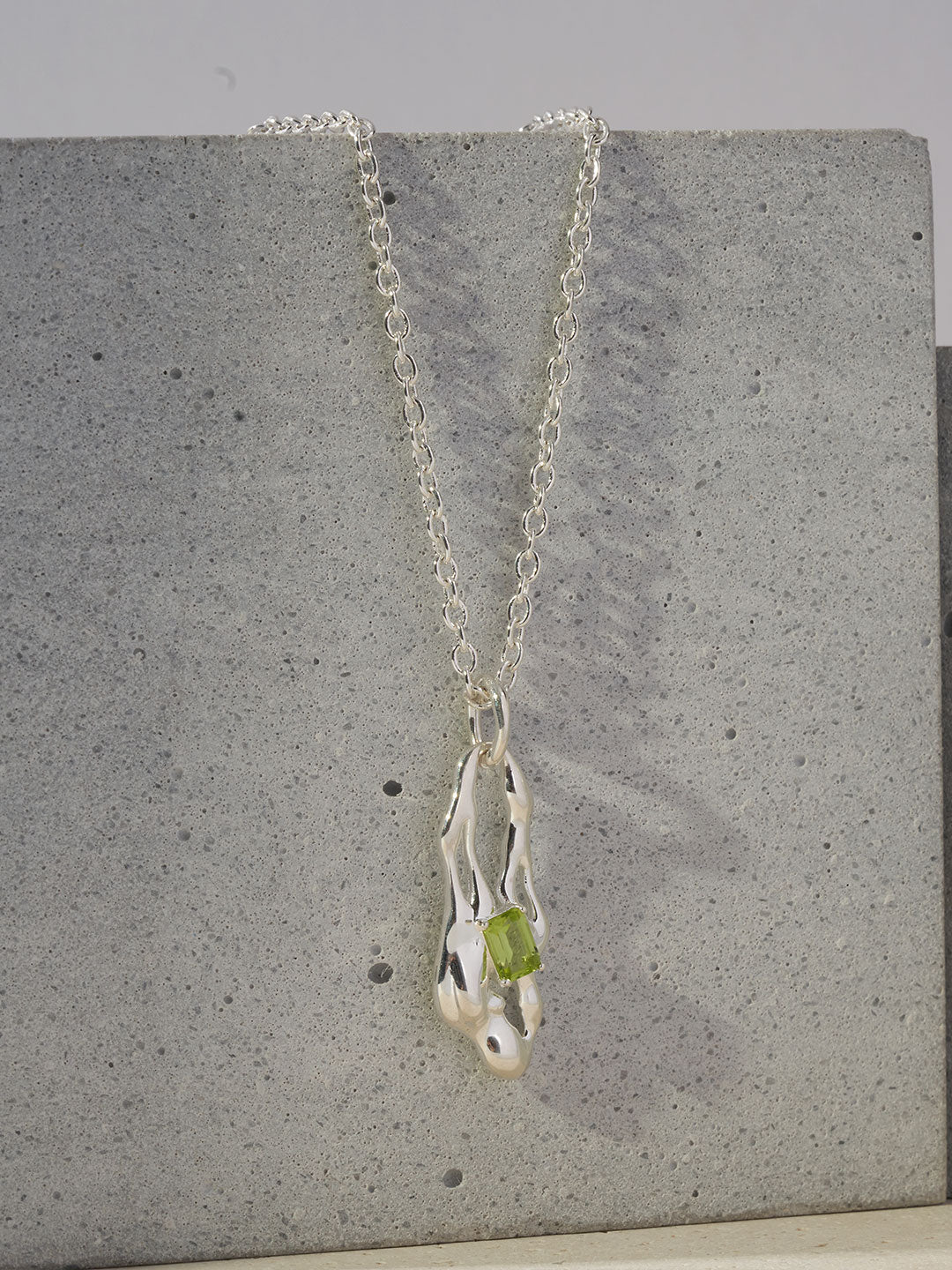 Silver necklace with dangling green peridot teardrop pendant