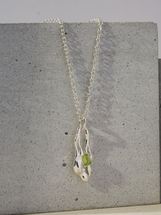 Silver necklace with dangling green peridot teardrop pendant