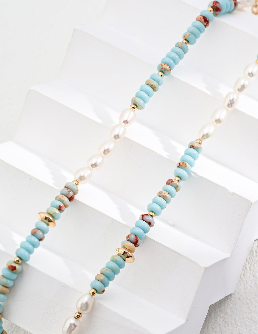 Turquoise heishi-bead strands with freshwater pearls and gold links in close view