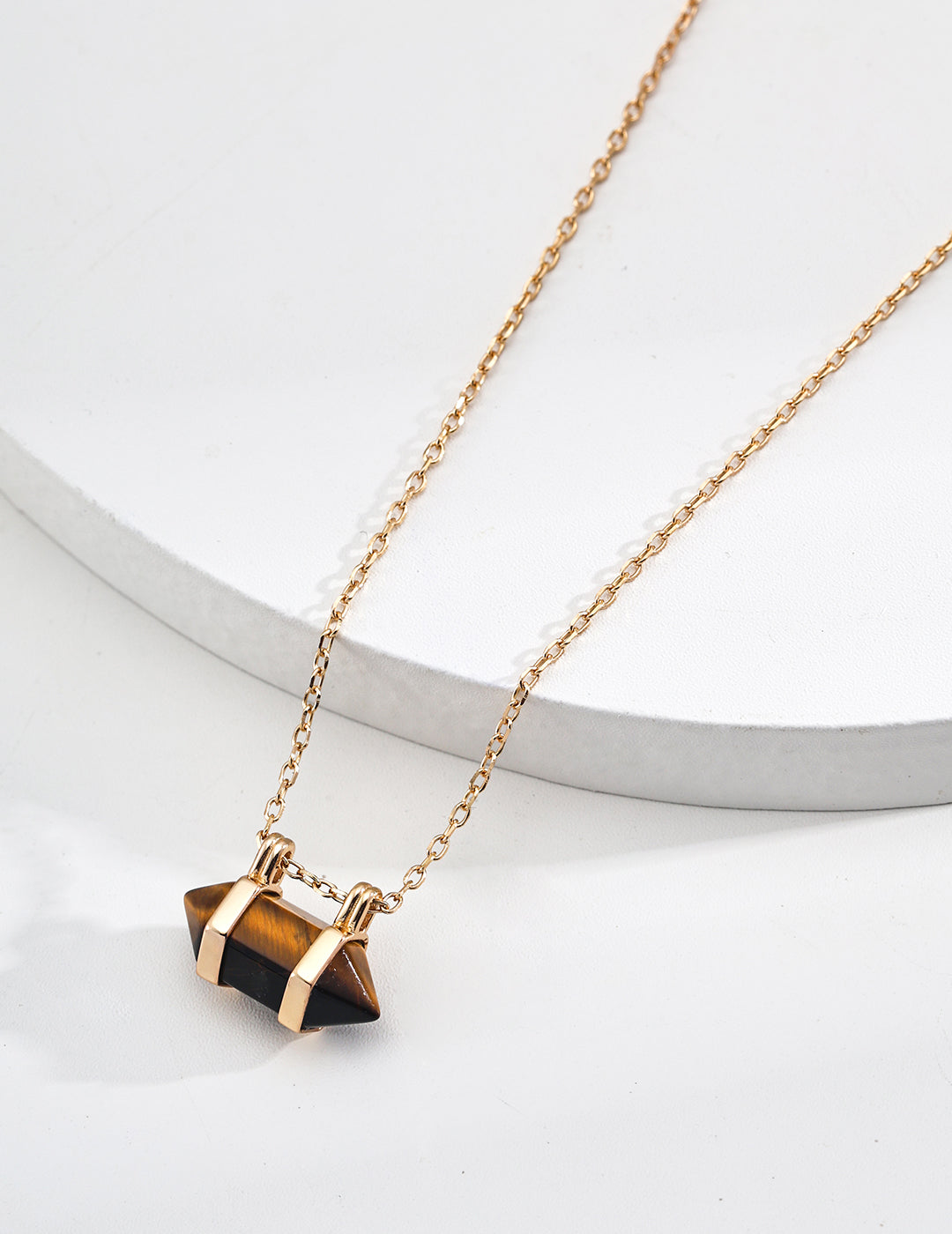 Gold chain necklace featuring a small dark geometric stone pendant charm