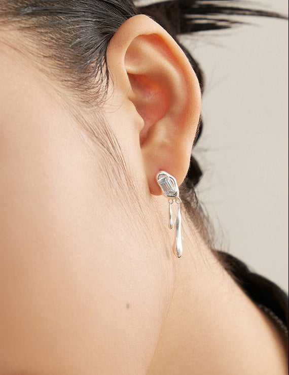Silver-tone drop earrings with blue square gemstone and dangling loop, on ear