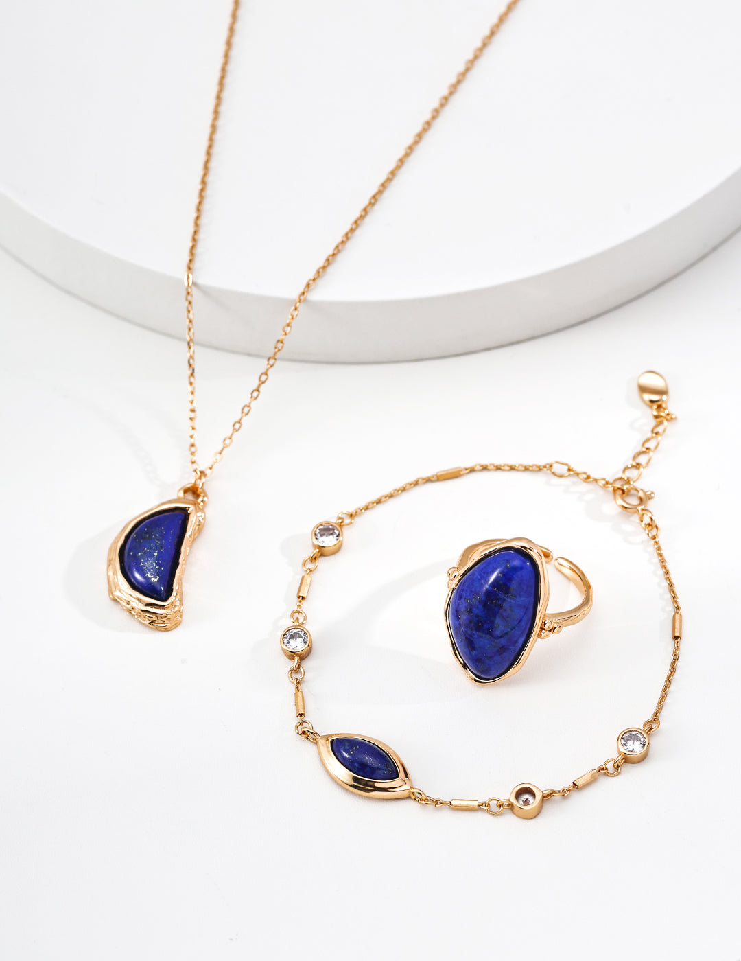 Gold-tone teardrop lapis pendant necklace on white pedestal with chain