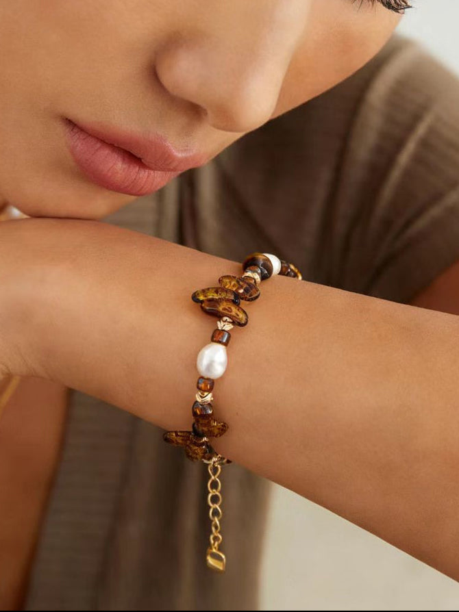 Bracelet on wrist: amber tiger eye beads with white pearls and gold-tone chain