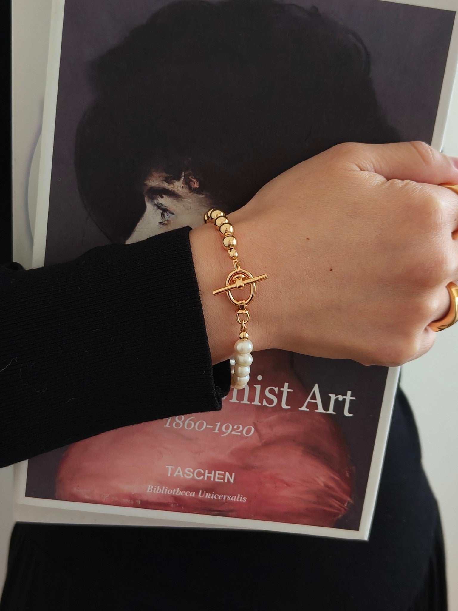 Gold and pearl bracelet worn on wrist with white freshwater pearls and toggle clasp