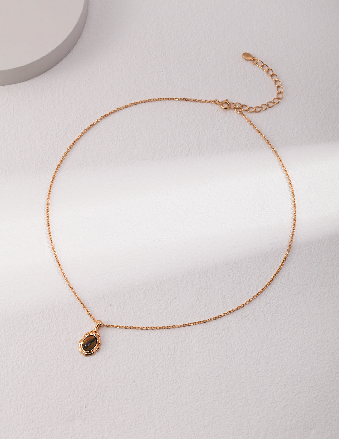 Gold-tone bead-link chain necklace with small oval dark stone pendant