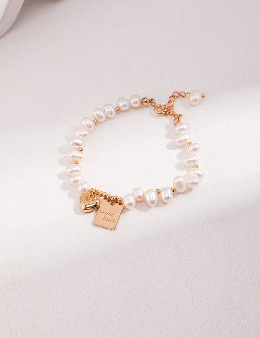 Pearl bracelet with gold-tone Good Luck charm and adjustable chain
