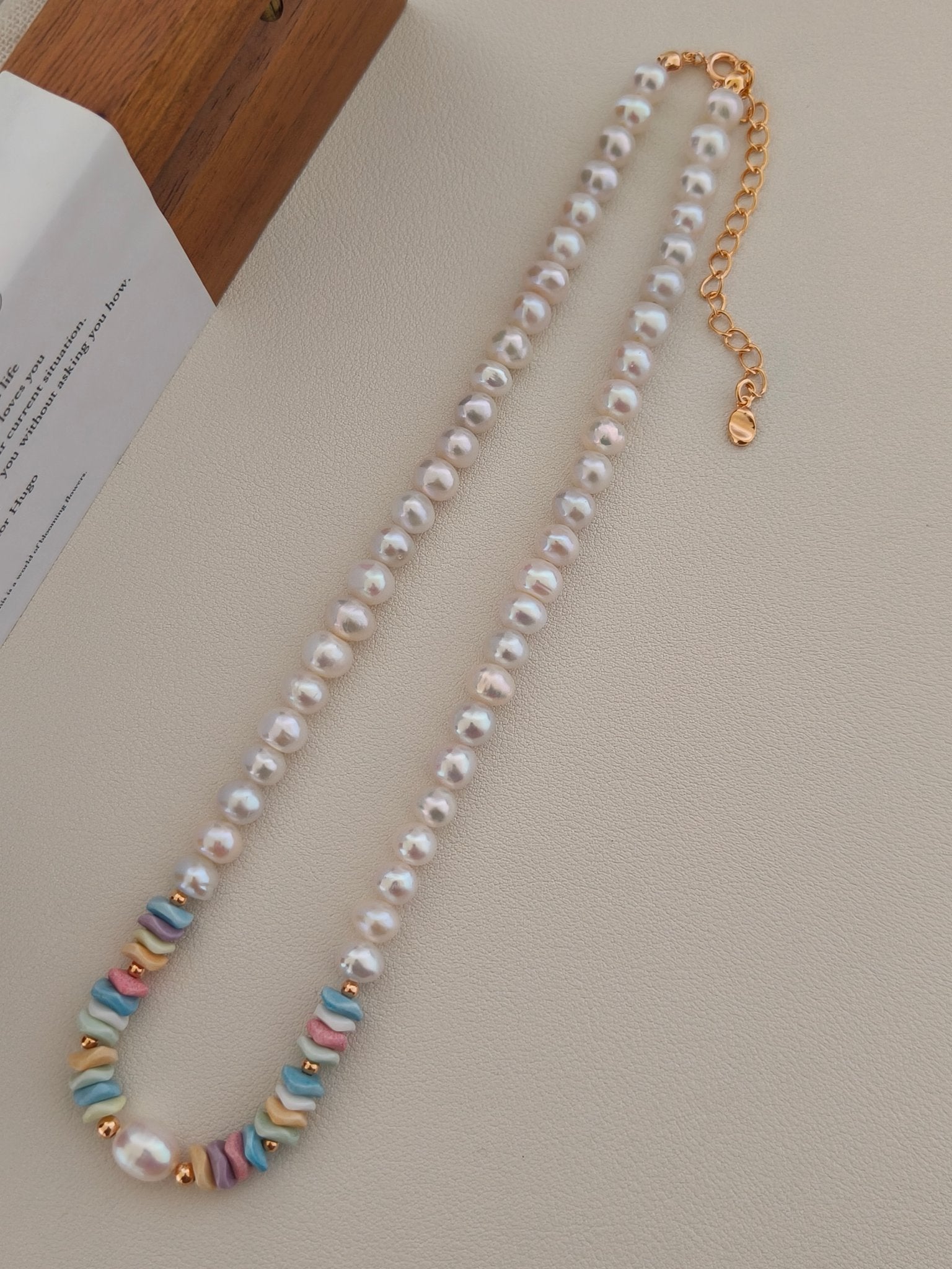 Layered view of freshwater pearl necklace with pastel rainbow bead sections.