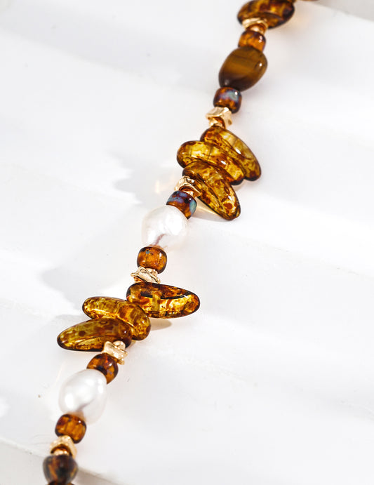 Close-up of amber tiger eye and white pearl beaded bracelet with gold chain links