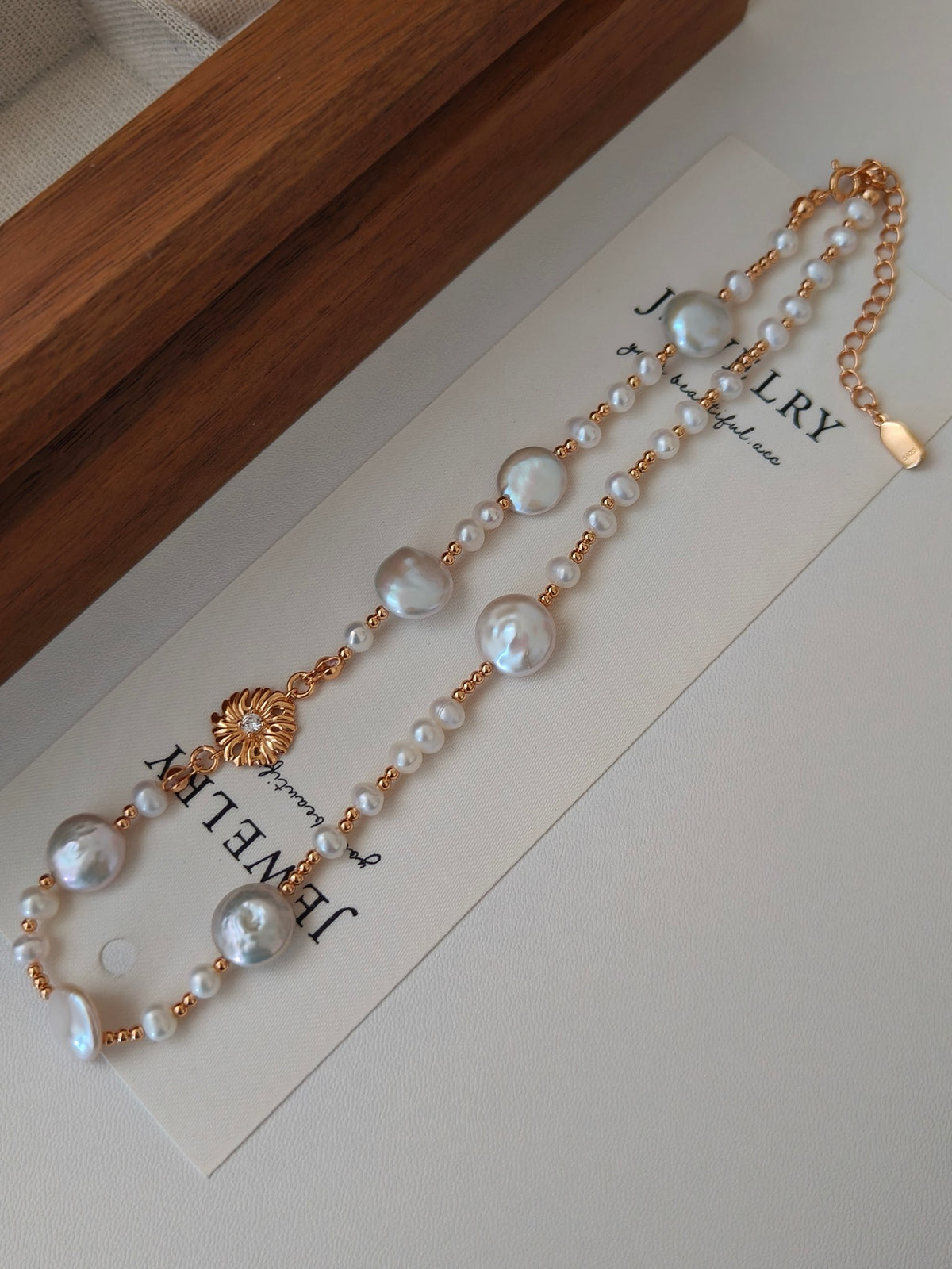 Gold-tone freshwater pearl necklace with round pearls and small gold floral centerpiece