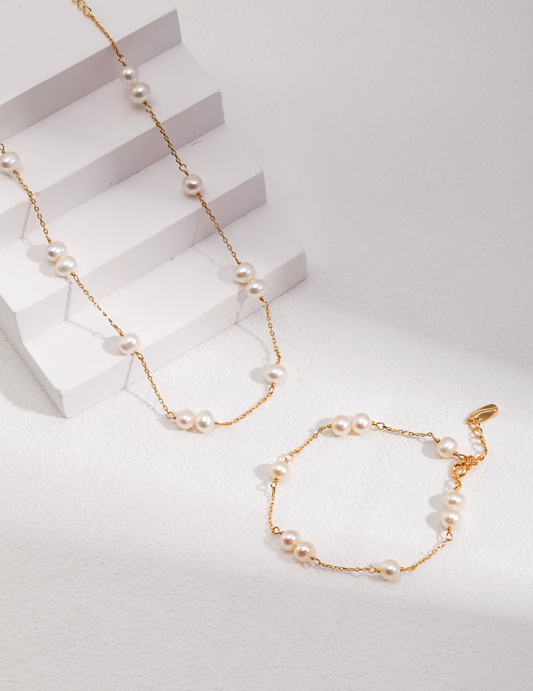 Pearl bracelet set with gold and silver tones, round white beads, and small charms