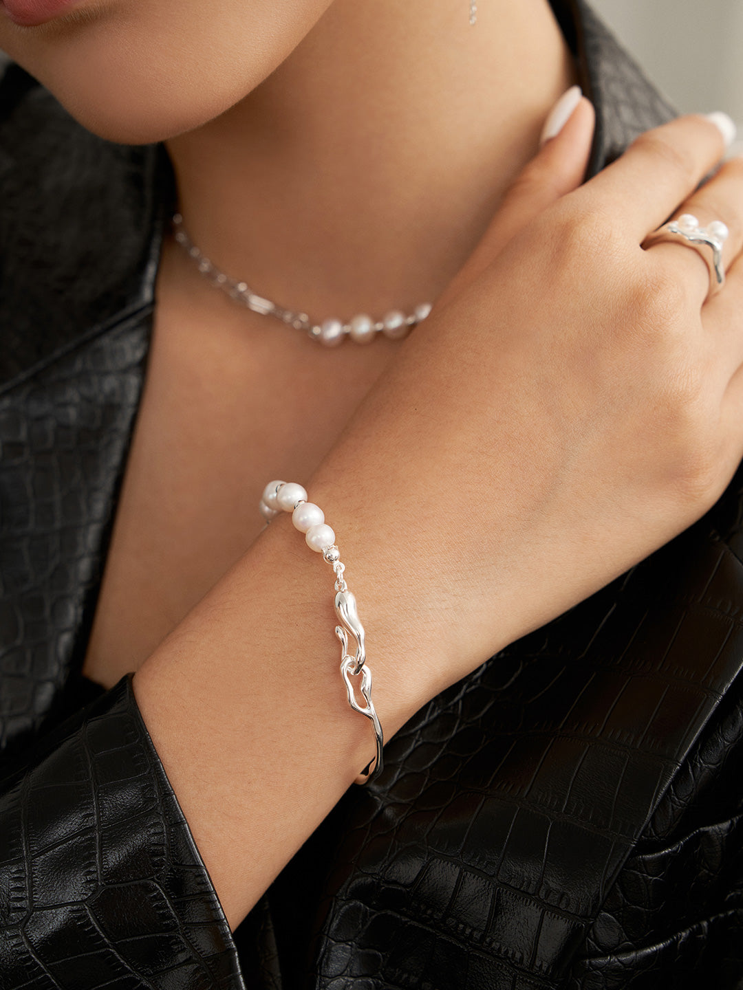 Gold-tone pearl bracelet with round beads and wavy chain link cuff on wrist