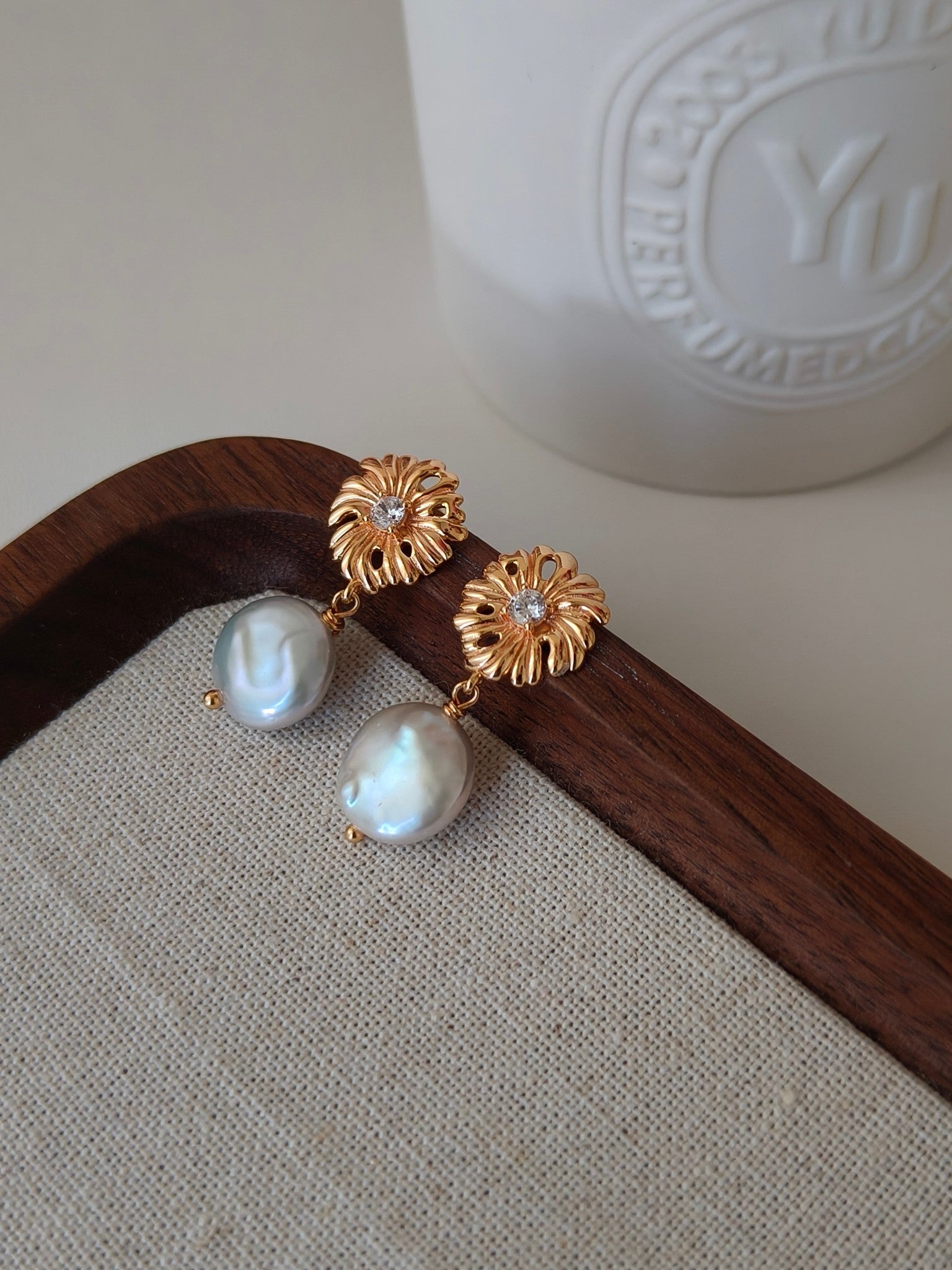 Gold-tone floral pearl drop earrings with small crystal details and lustrous white pearls