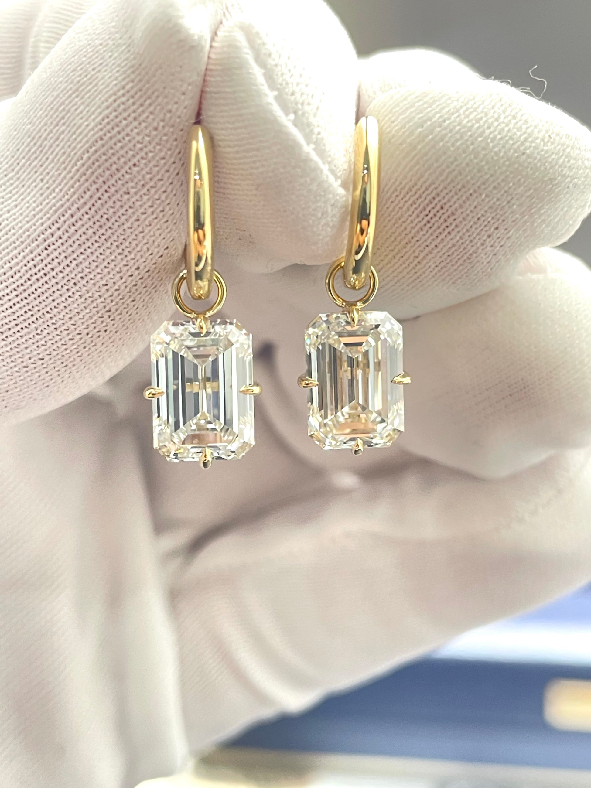 Gold hoop-to-drop lab diamond earrings with emerald-cut stones.