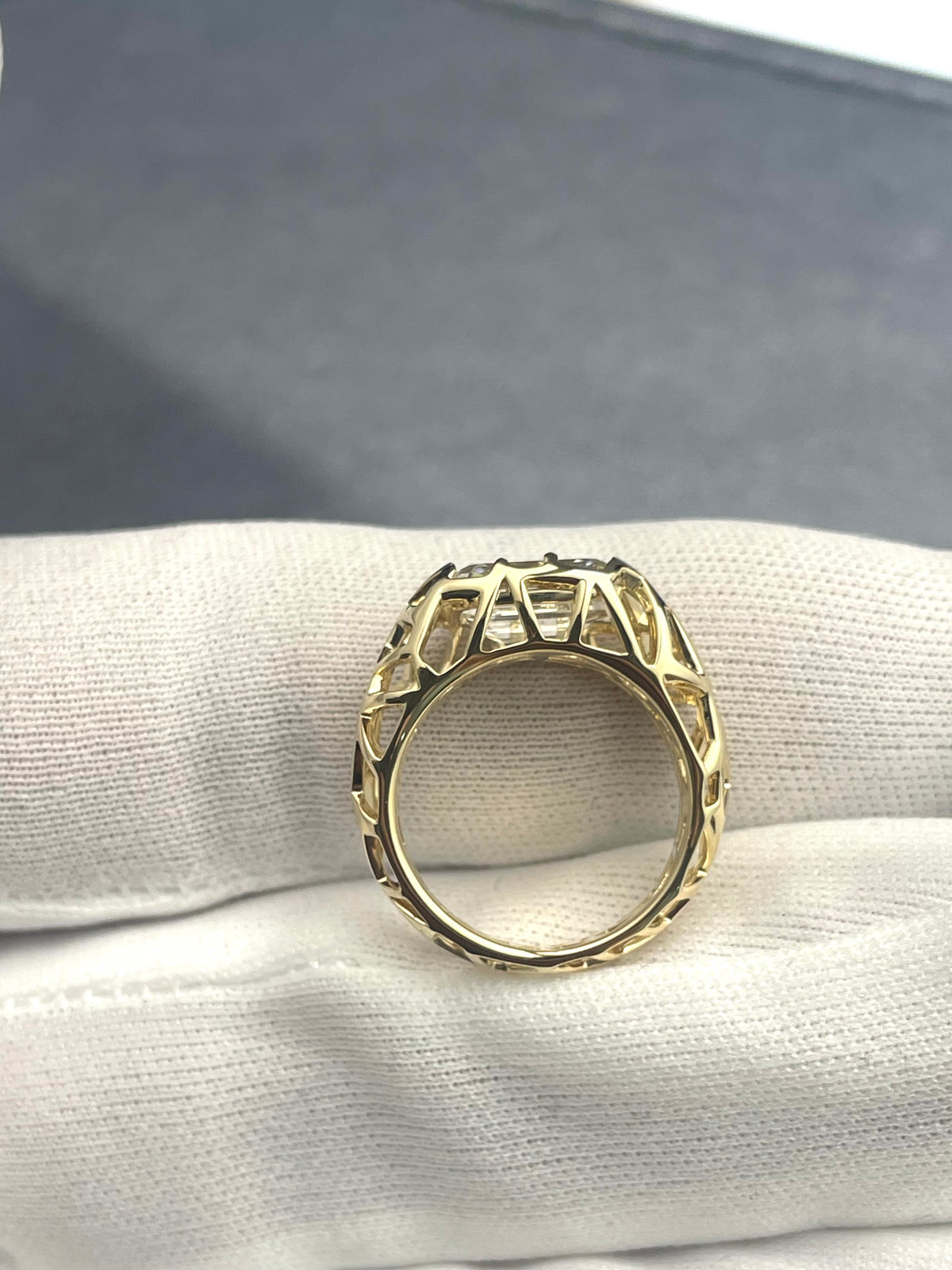 Gold bird-nest style lab diamond ring with emerald-cut center stone and side lattice