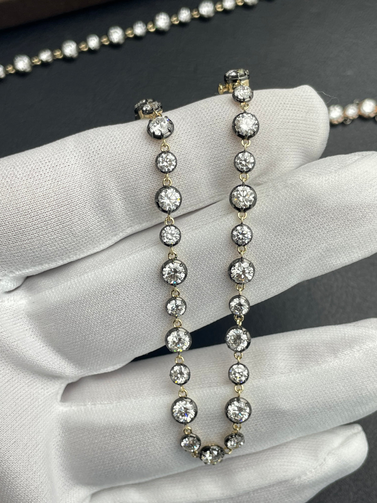 Gold-tone diamond tennis bracelet close-up with round stones on white gloves